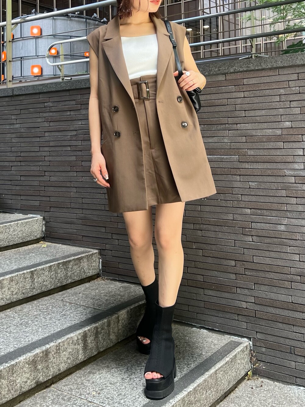 ブラウン系のベスト、ブラウン系のスカート、ホワイト系のニット/セーターを着用したレディースの夏コーディネートの7枚目の写真