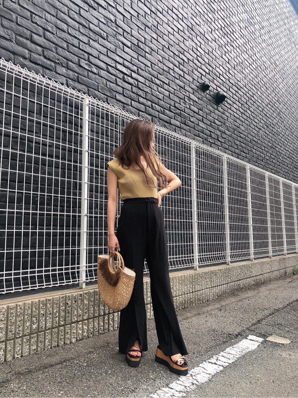 ブラック系のスラックス、ベージュ系のかごバッグ、ブラック系のサンダルを着用したレディースの夏コーディネートの3枚目の写真