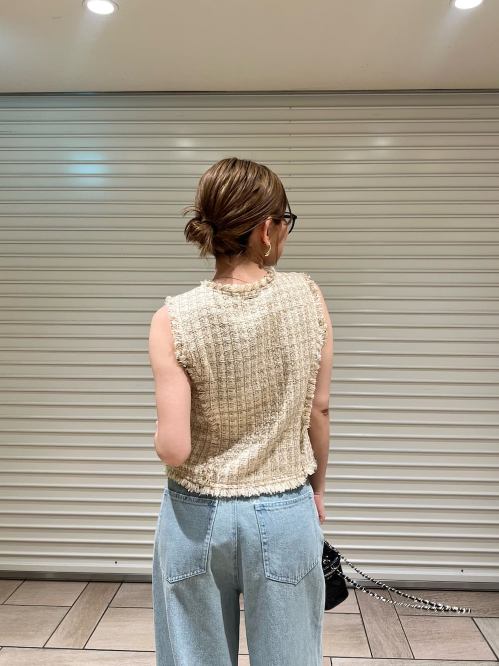 ベージュ系のベスト、ブルー系のデニムパンツを着用したレディースの夏コーディネートの5枚目の写真