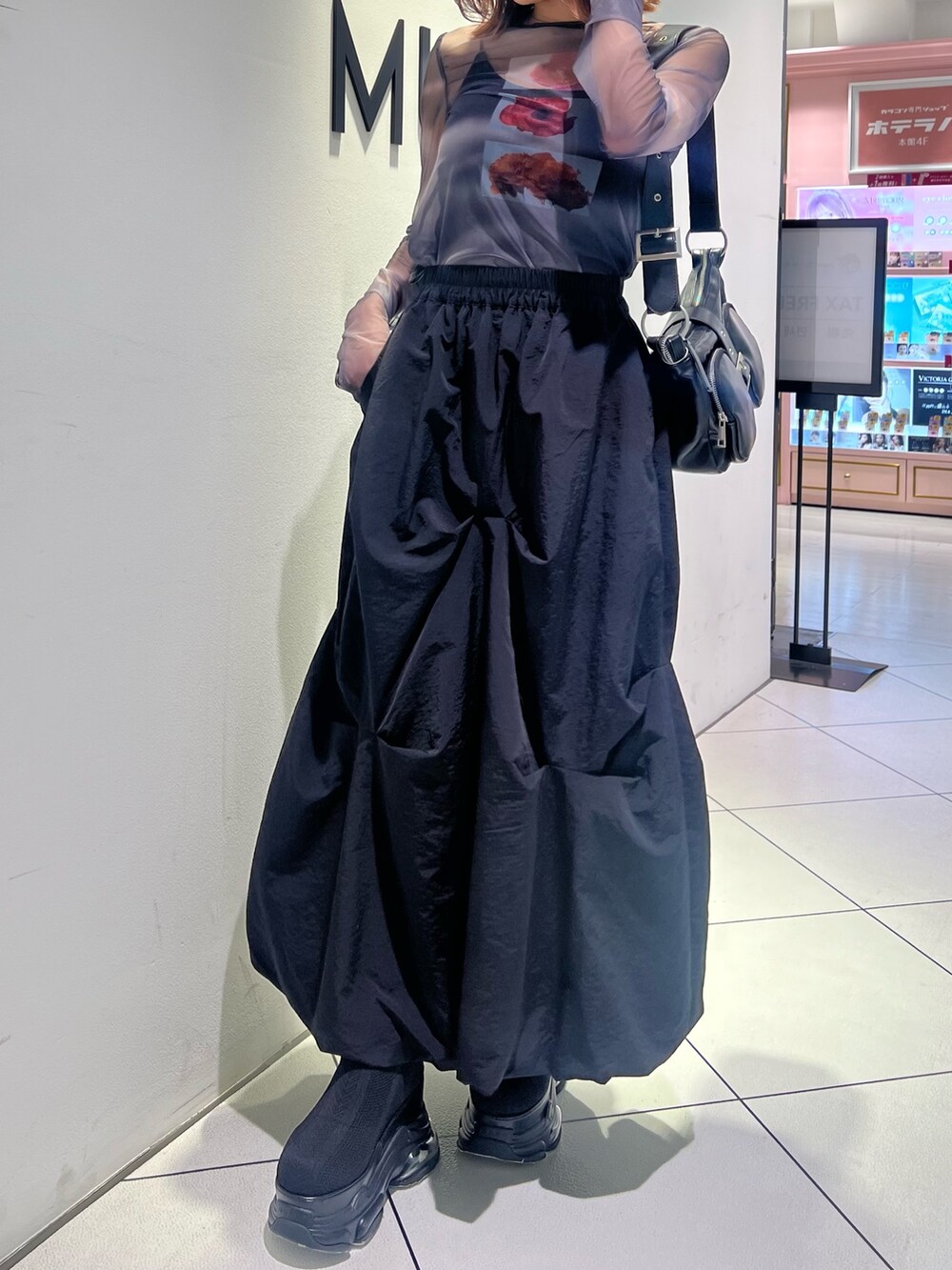 ブラック系のTシャツ/カットソー、ブラック系のスカート、ブラック系のブーツを着用したレディースの春コーディネートの8枚目の写真