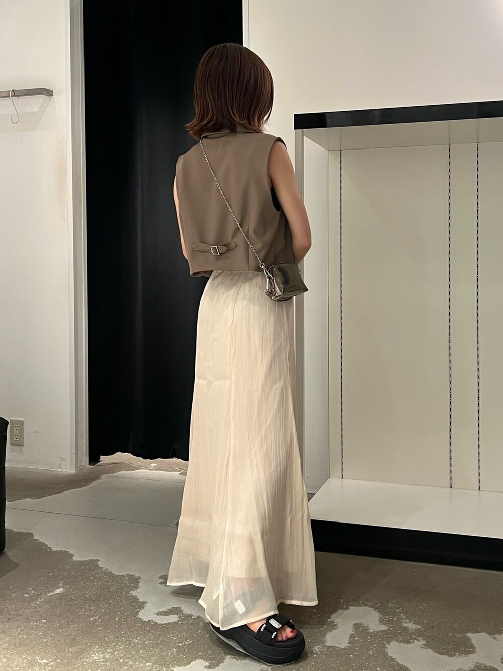 ブラック系のサンダル、ホワイト系のスカート、ゴールド系のショルダーバッグを着用したレディースの夏コーディネートの2枚目の写真