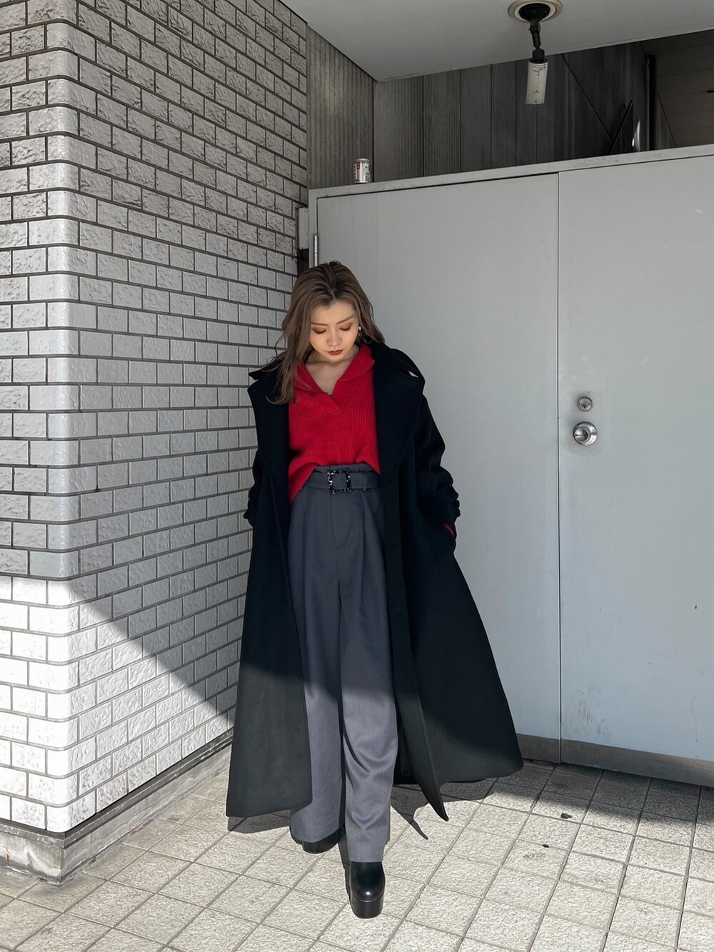 レッド系のニット/セーター、ブラック系のダウンジャケット/コート、ブラック系のブーツを着用したレディースの秋コーディネートの4枚目の写真