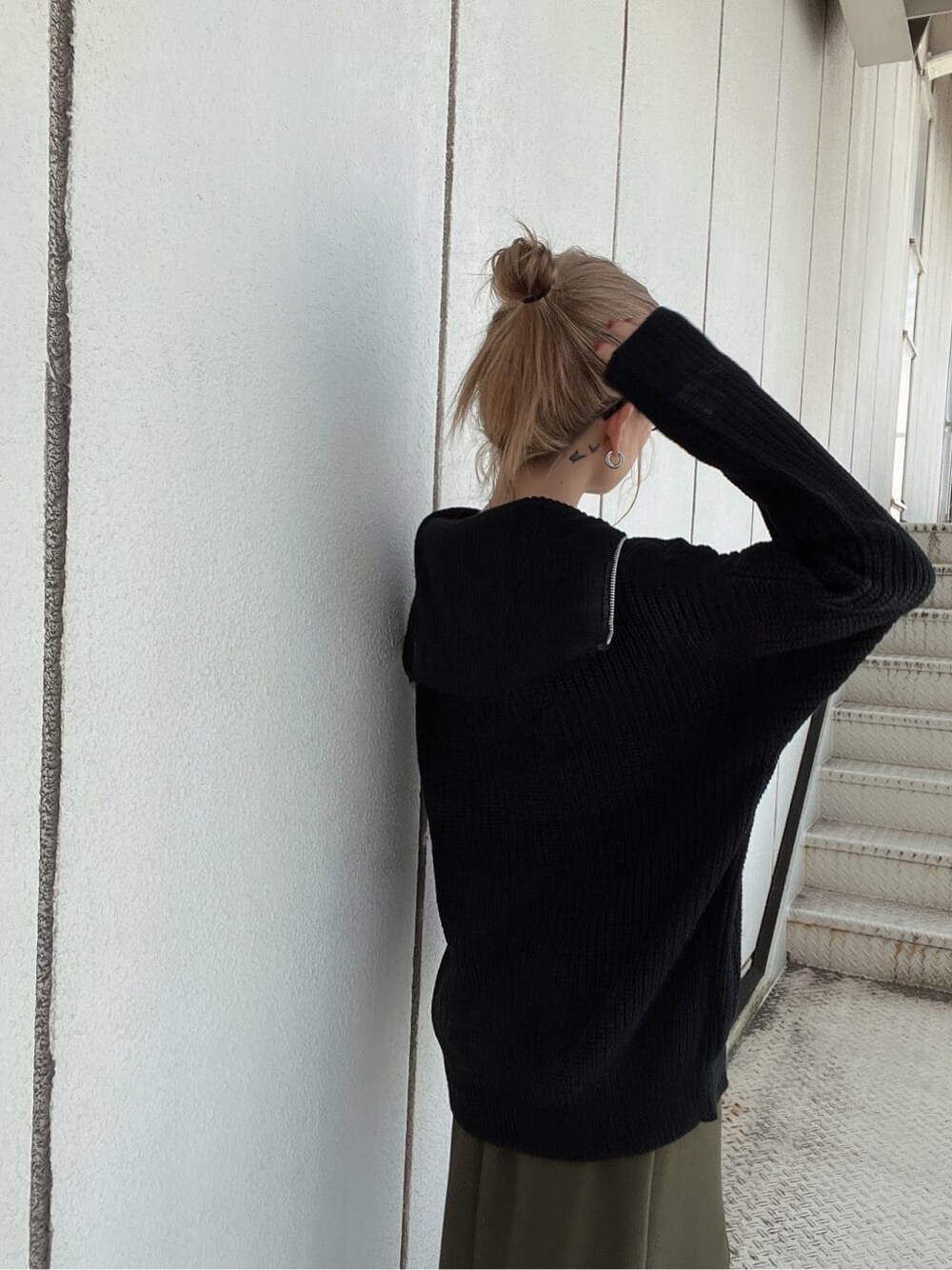 グリーン系のスカート、ブラック系のブーツ、ブラック系のニット/セーターを着用したレディースの秋コーディネートの5枚目の写真