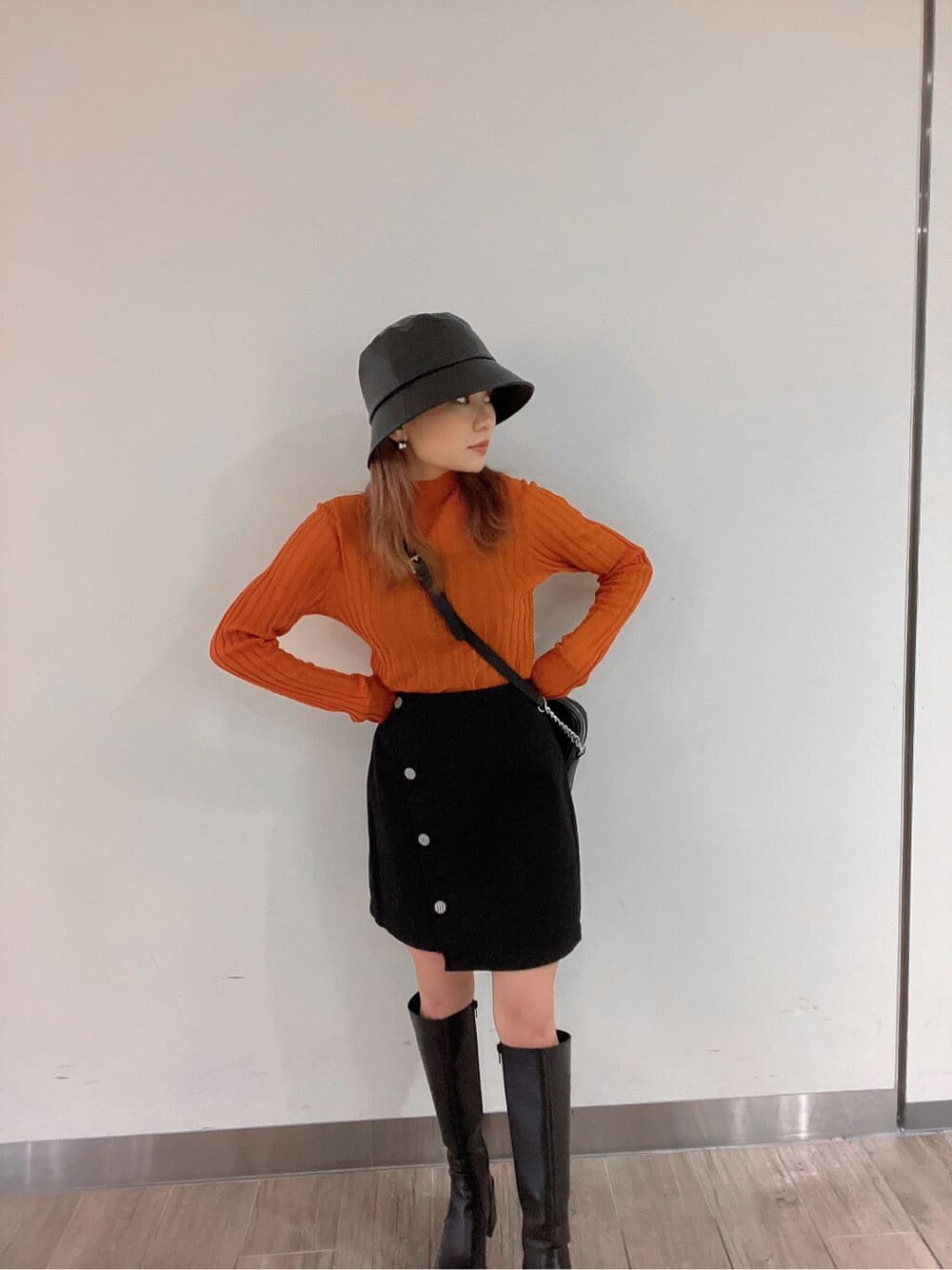 ブラック系のブーツ、オレンジ系のニット/セーター、ブラック系のスカートを着用したレディースの秋コーディネートの6枚目の写真