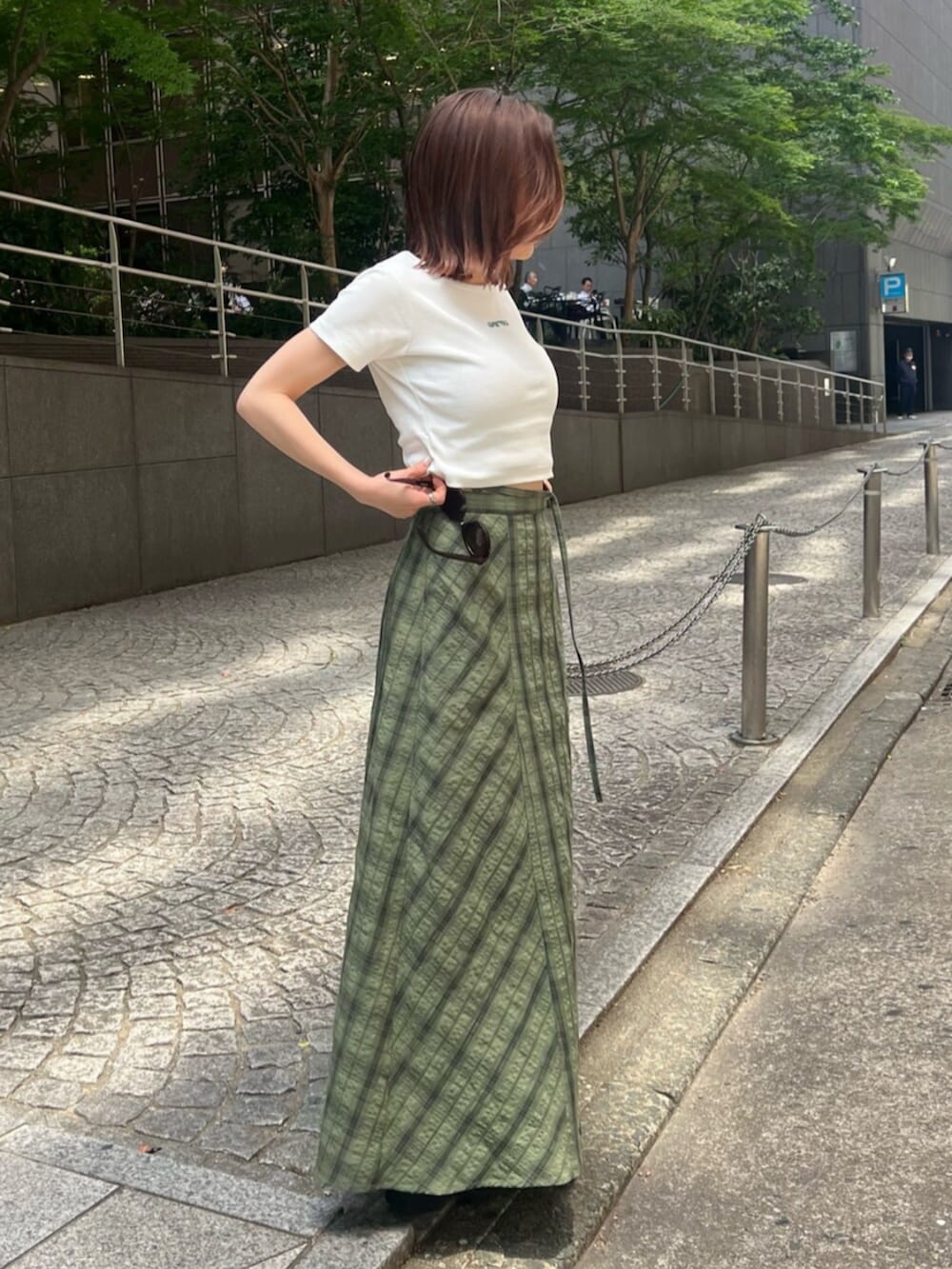 ブラック系のサンダル、ホワイト系のTシャツ/カットソー、グリーン系のスカートを着用したレディースの春コーディネートの3枚目の写真