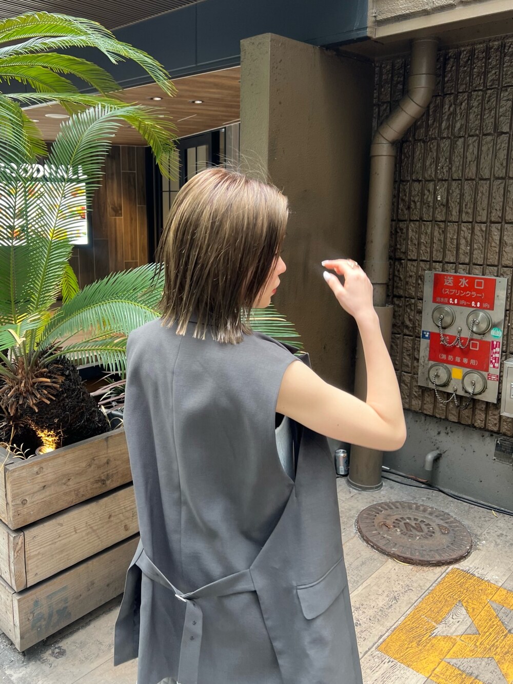 ホワイト系のワンピース、グレー系のベスト、ブラック系のサンダルを着用したレディースの春コーディネートの5枚目の写真