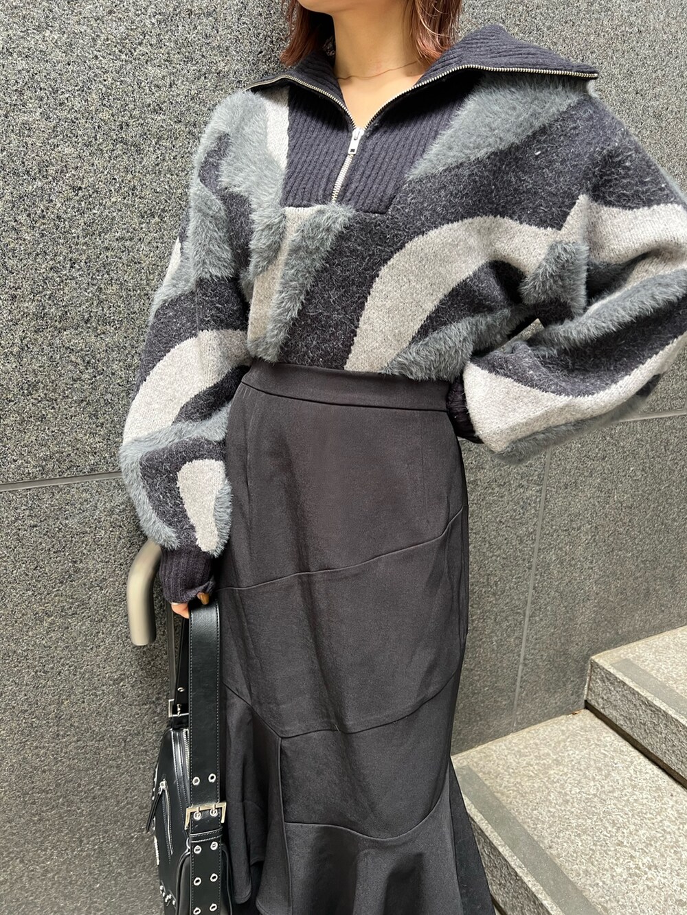 ブラック系のニット/セーター、ブラウン系のブーツ、ブラック系のスカートを着用したレディースの秋コーディネートの8枚目の写真