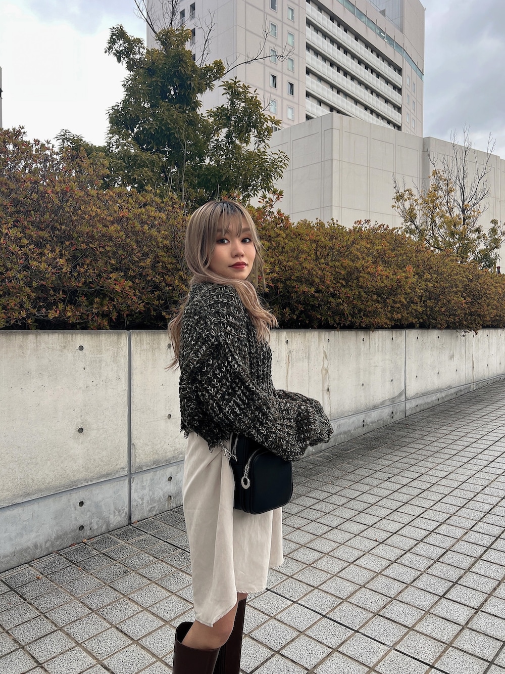 グリーン系のワンピース、ブラック系のショルダーバッグ、ブラウン系のブーツを着用したレディースの冬コーディネートの5枚目の写真