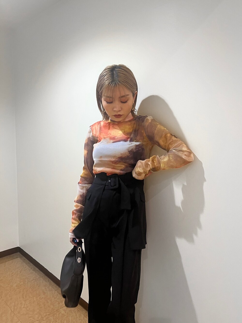 オレンジ系のTシャツ/カットソー、ブラック系のブーツ、ブラック系のスラックスを着用したレディースの夏コーディネートの4枚目の写真