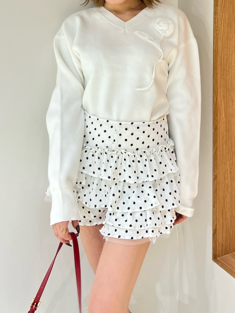 ホワイト系のニット/セーター、ホワイト系のその他パンツ、レッド系のハンドバッグを着用したレディースの冬コーディネートの5枚目の写真