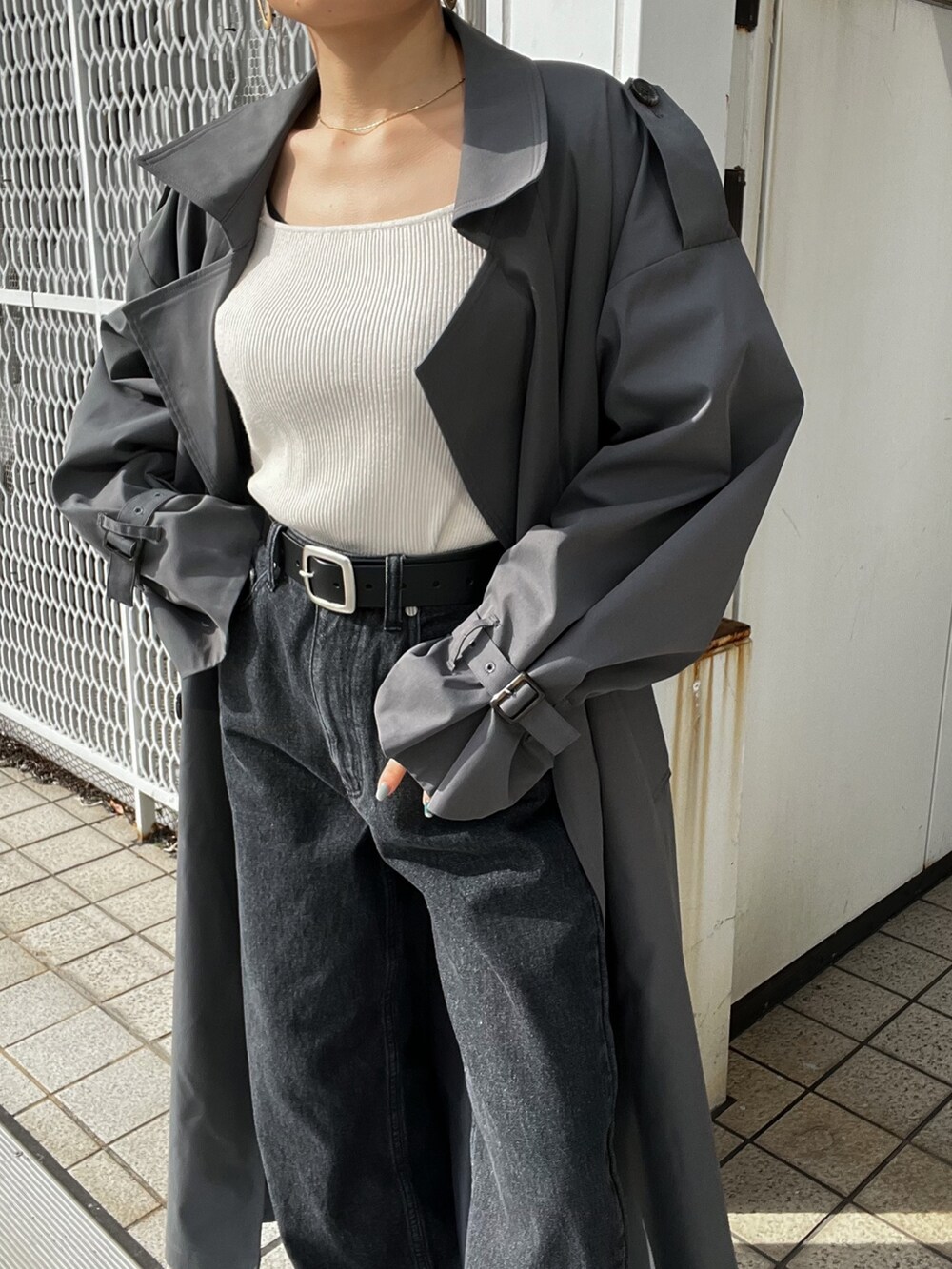 グレー系のトレンチコート、ブラック系のデニムパンツ、ブラック系のベルトを着用したレディースの冬コーディネートの7枚目の写真