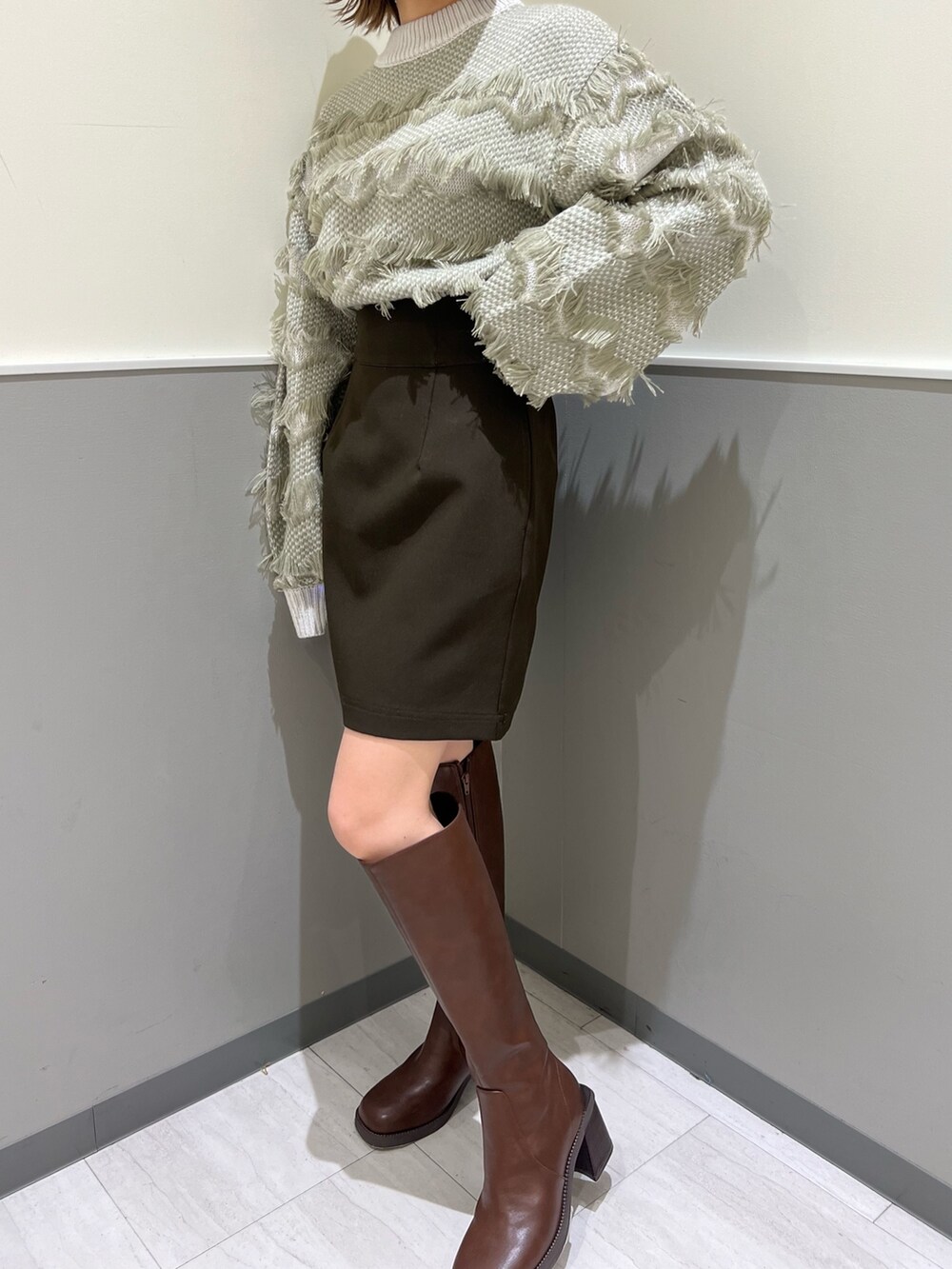 ベージュ系のニット/セーター、ブラウン系のスカート、ブラウン系のブーツを着用したレディースの秋コーディネートの7枚目の写真