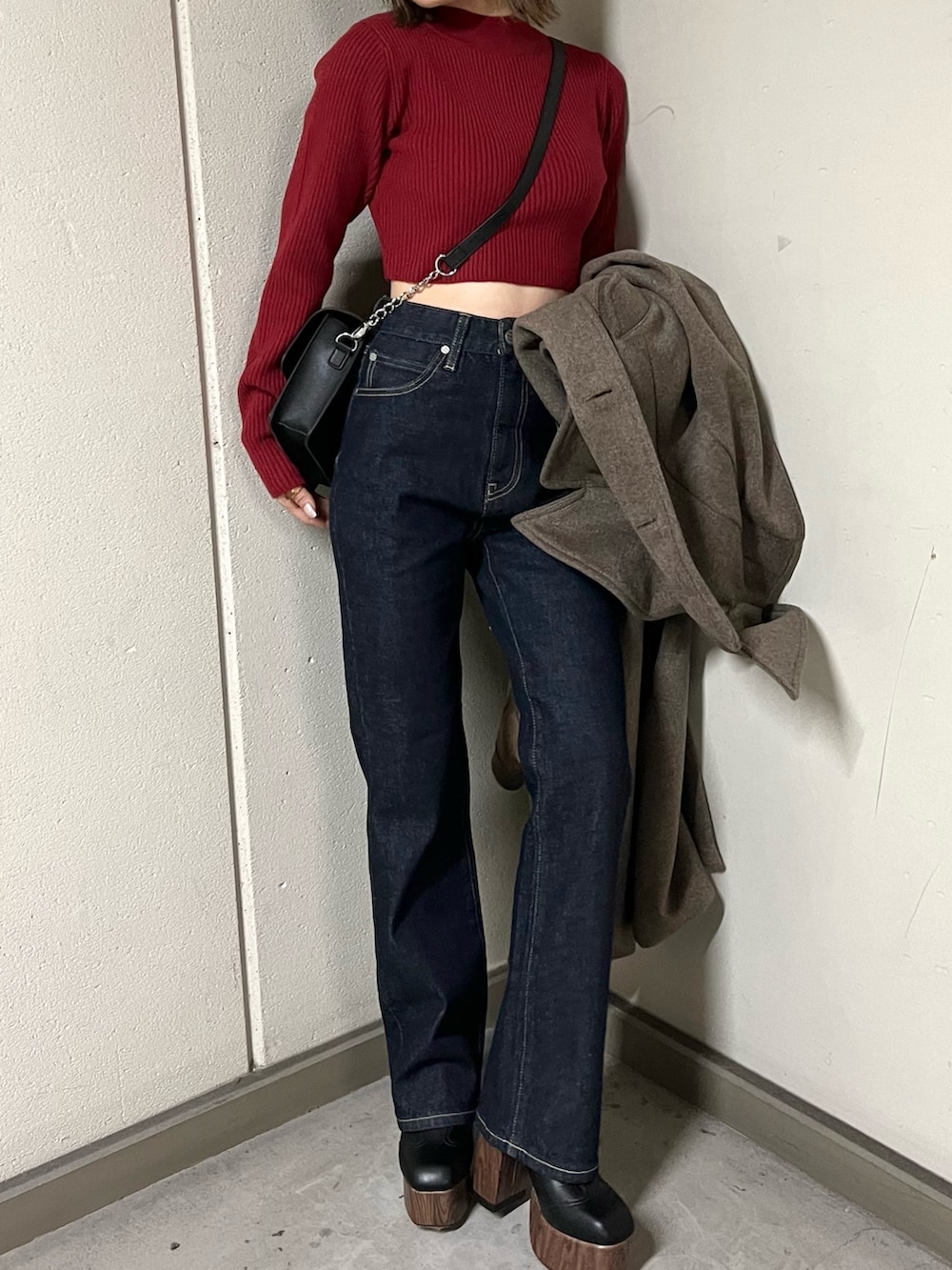 ブルー系のデニムパンツ、ブラウン系のチェスターコート、レッド系のニット/セーターを着用したレディースの秋コーディネートの7枚目の写真