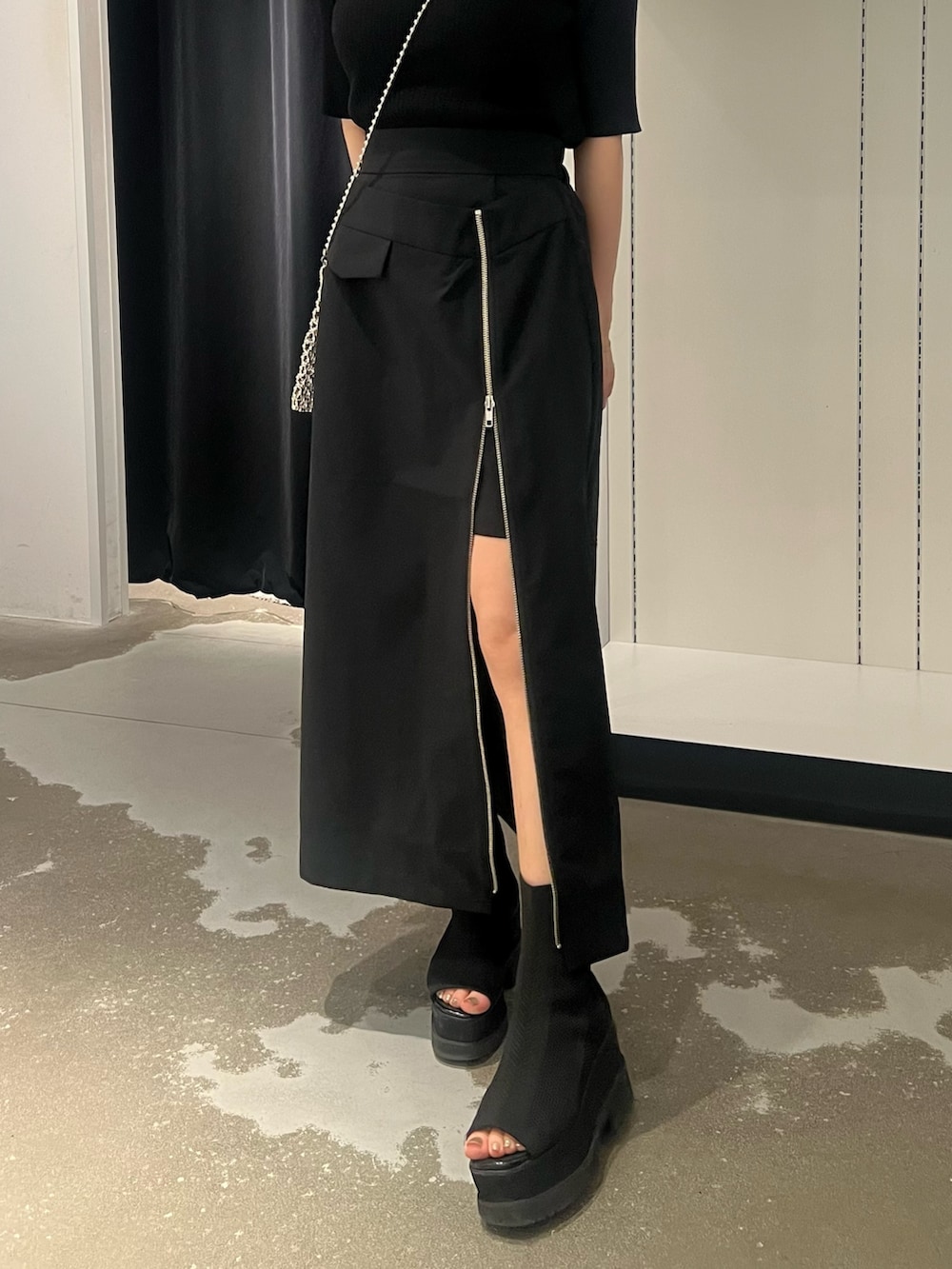 ブラック系のスカート、ブラック系のサンダル、シルバー系のショルダーバッグを着用したレディースの春コーディネートの5枚目の写真