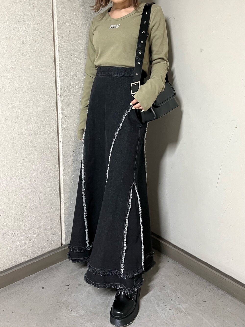 グリーン系のTシャツ/カットソー、ブラック系のデニムスカート、ブラック系のブーツを着用したレディースの冬コーディネートの6枚目の写真