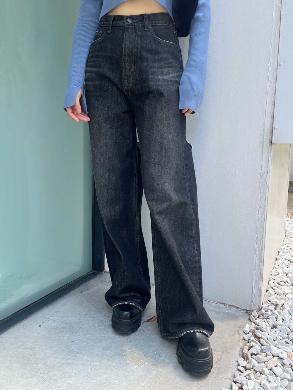 ブラック系のデニムパンツ、ブラック系のブーツ、ブルー系のニット/セーターを着用したレディースの秋コーディネートの4枚目の写真