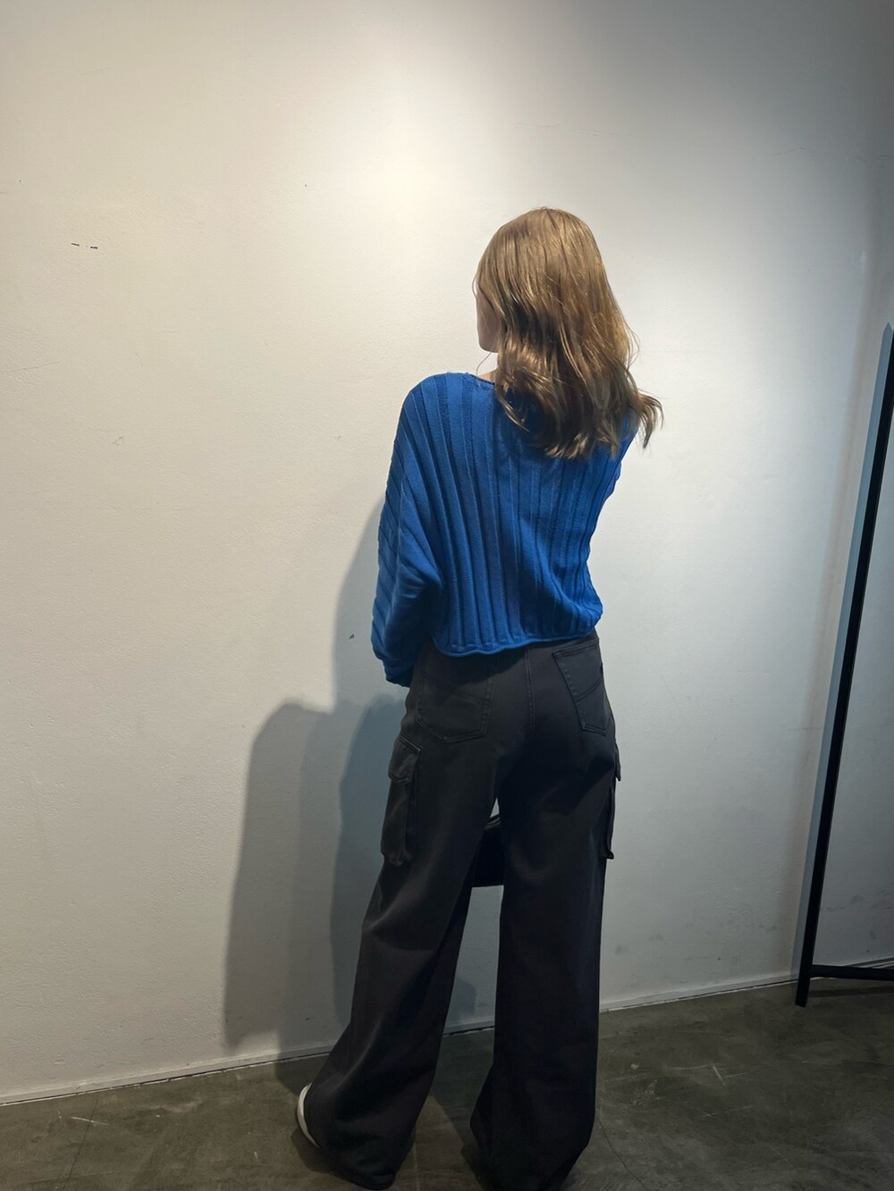 ブラック系のハンドバッグ、ブラック系のデニムパンツ、ブルー系のニット/セーターを着用したレディースの冬コーディネートの4枚目の写真