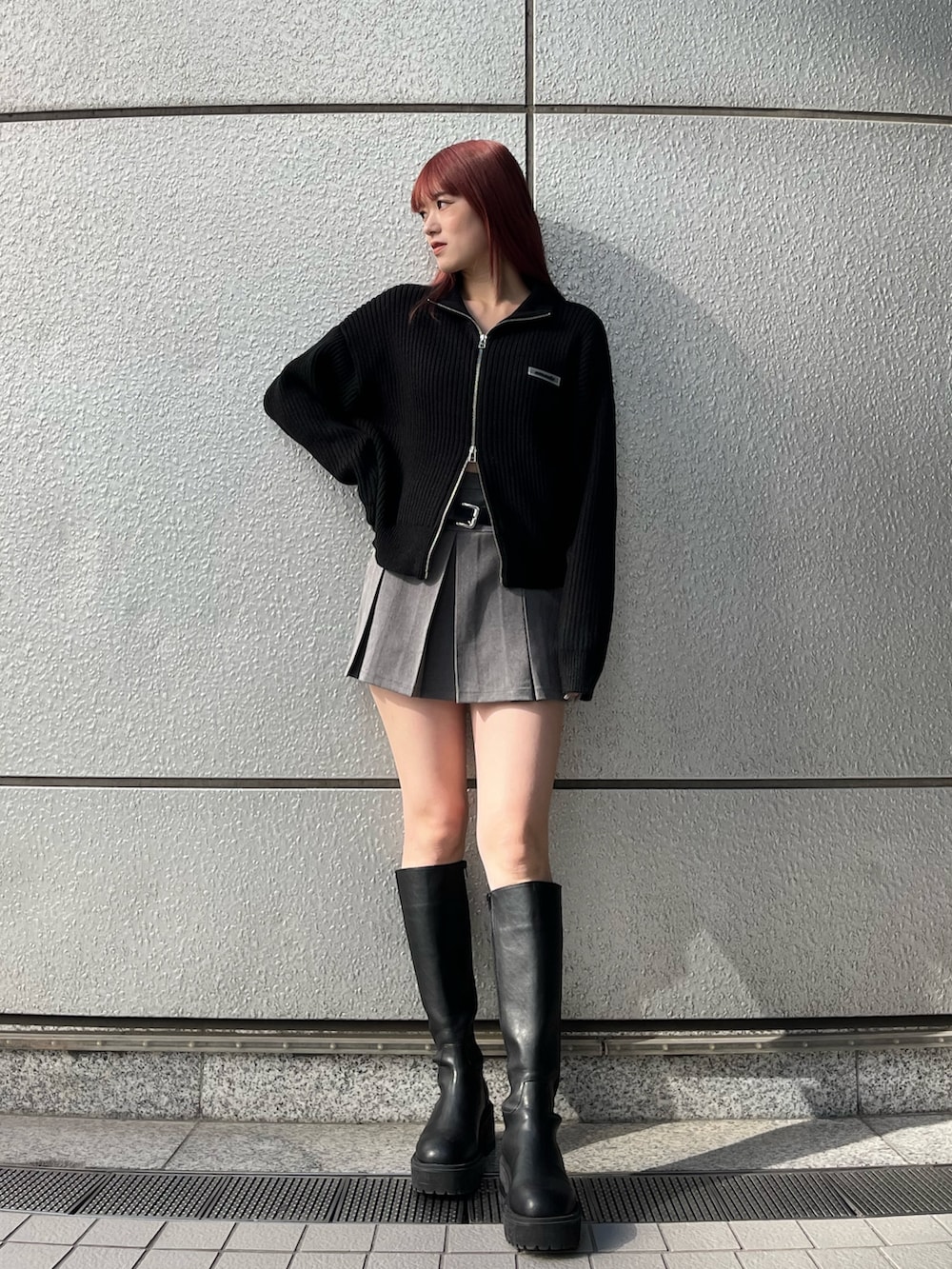 グレー系のスカート、ブラック系のブーツ、ブラック系のニット/セーターを着用したレディースの秋コーディネートの2枚目の写真