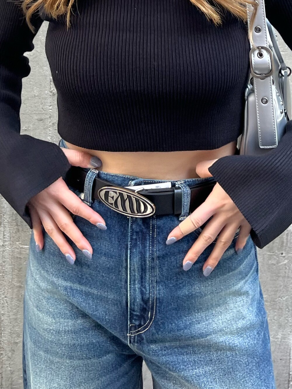 ブルー系のデニムパンツ、シルバー系のハンドバッグ、ブラック系のニット/セーターを着用したレディースの春コーディネートの7枚目の写真