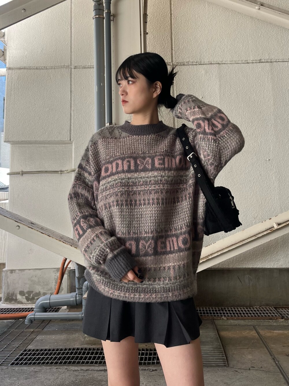 グレー系のスカート、ピンク系のニット/セーター、ブラック系のブーツを着用したレディースの冬コーディネートの6枚目の写真