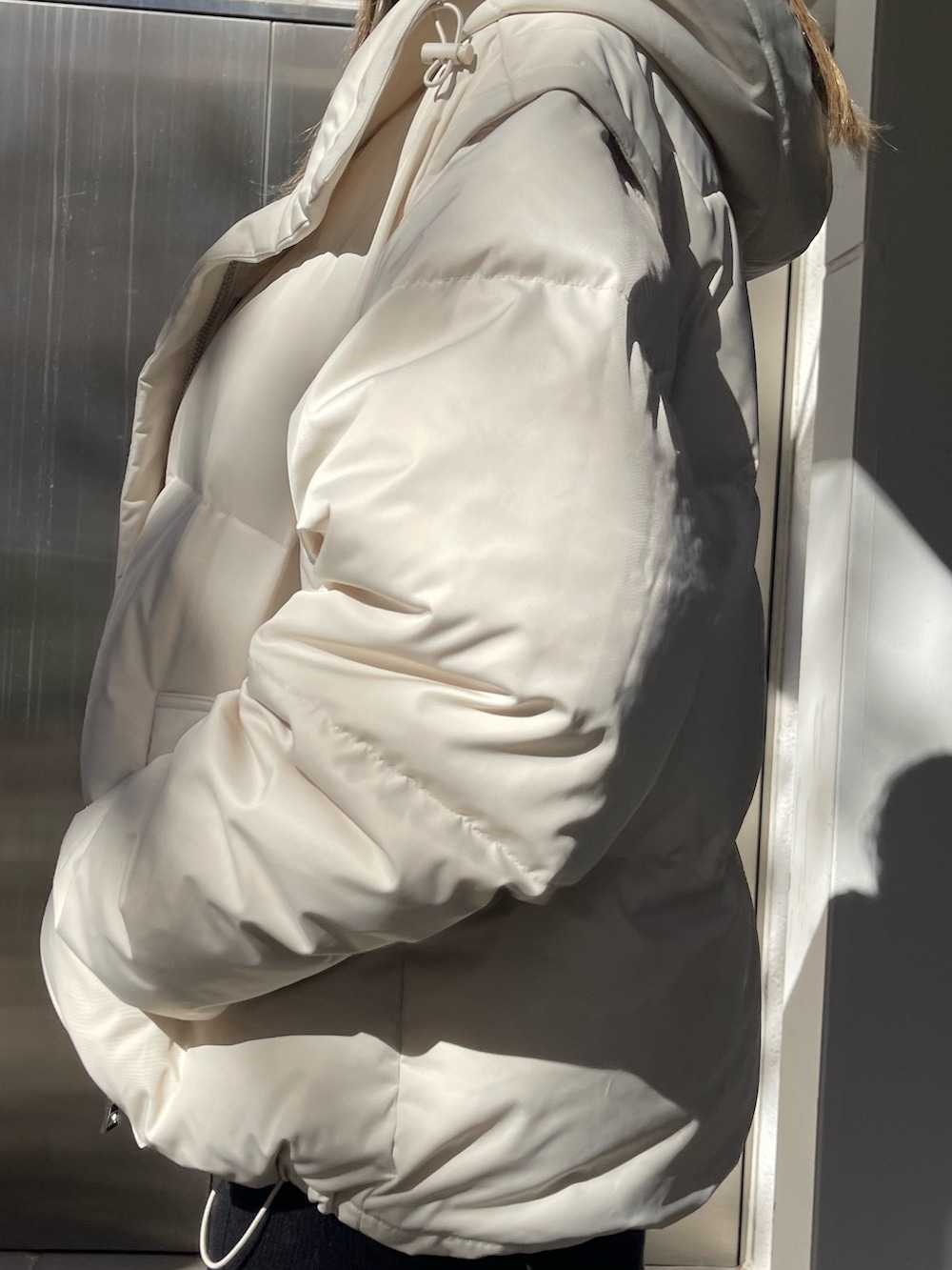 ホワイト系のダウンジャケット/コート、ブラック系のワンピース、ブラック系のブーツを着用したレディースの秋コーディネートの5枚目の写真