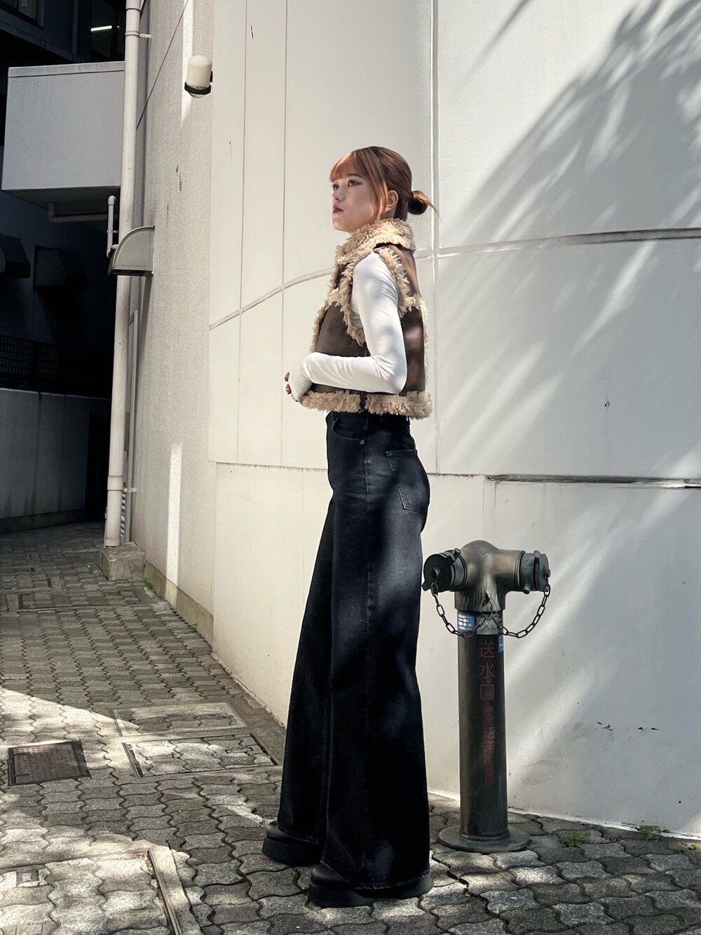 ブラック系のデニムパンツ、ブラック系のブーツ、ブラウン系のベストを着用したレディースの秋コーディネートの3枚目の写真