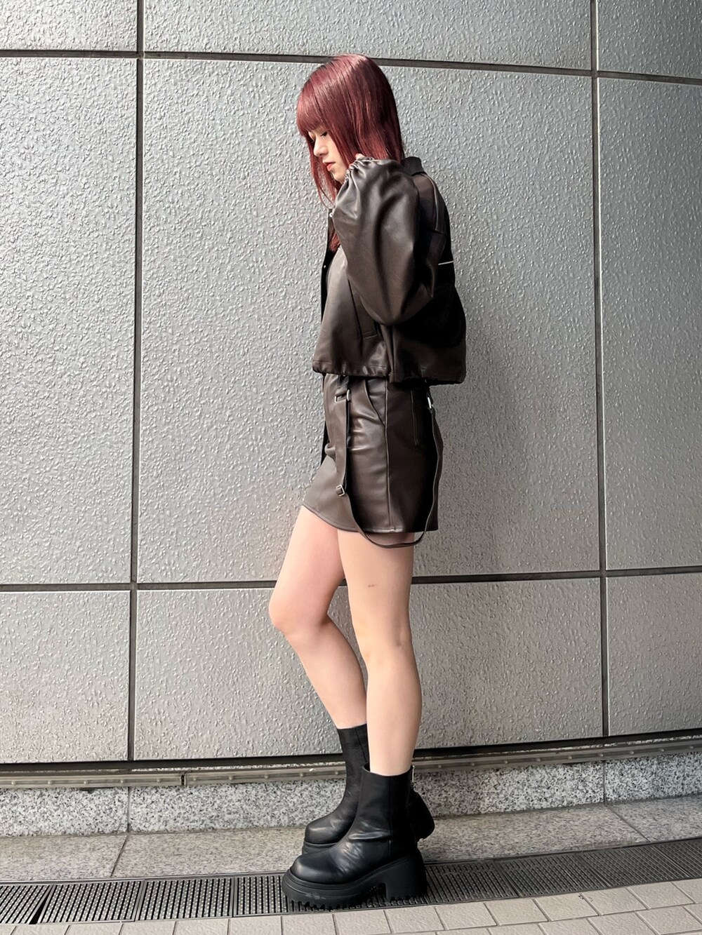 ブラウン系のスカート、ブラック系のニット/セーター、ブラウン系のブルゾンを着用したレディースの冬コーディネートの2枚目の写真