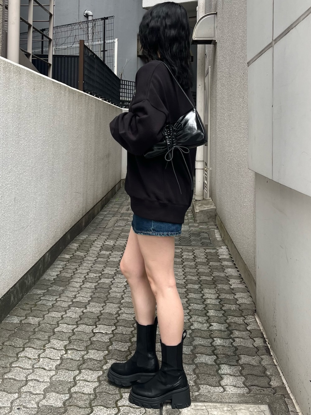 ブラック系のブーツ、ブラック系のショルダーバッグ、ブラック系のスウェットを着用したレディースの夏コーディネートの2枚目の写真