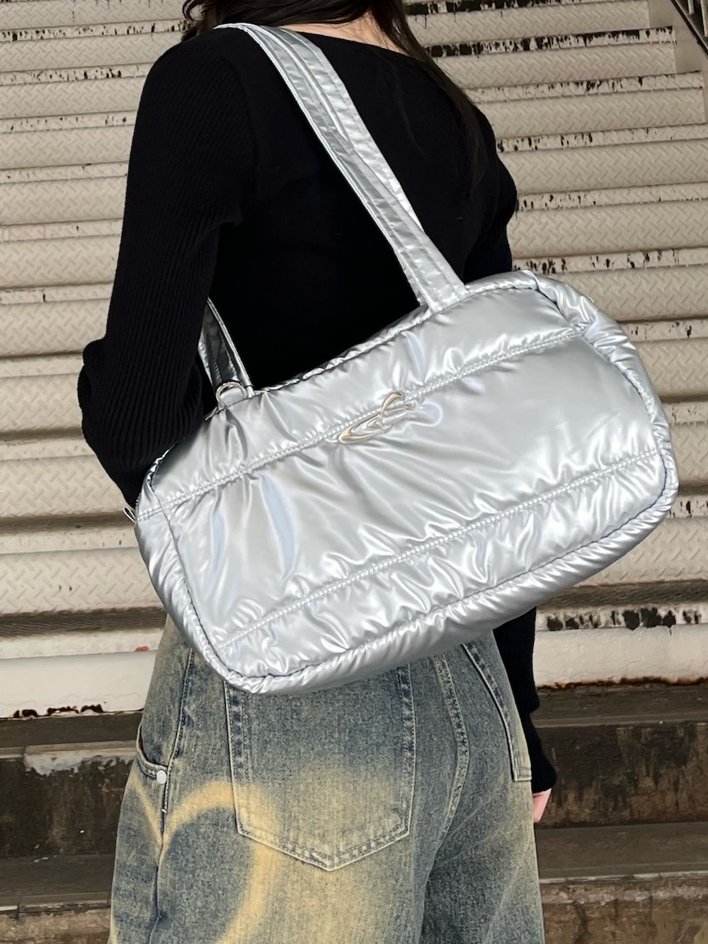 シルバー系のボストンバッグ、ブルー系のデニムパンツ、ブラック系のニット/セーターを着用したレディースの冬コーディネートの7枚目の写真