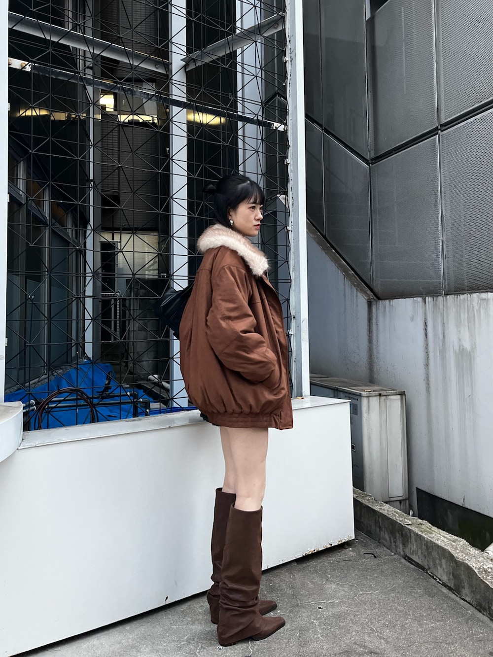 ブラック系のスカート、ブラウン系のブーツ、ブラック系のニット/セーターを着用したレディースの冬コーディネートの2枚目の写真