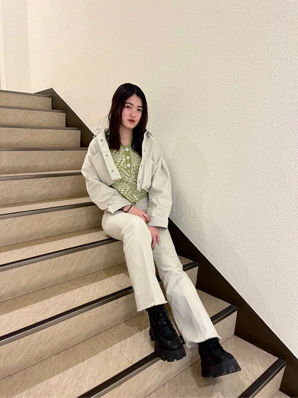 ブラック系のブーツ、ホワイト系のデニムジャケット、その他のポロシャツを着用したレディースの春コーディネートの2枚目の写真