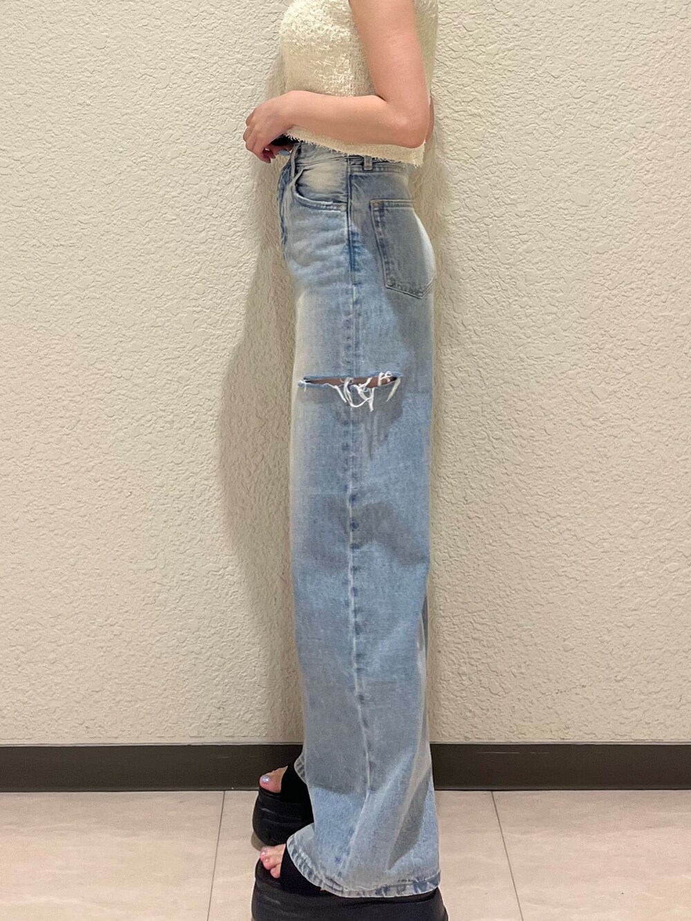 ブルー系のデニムパンツ、ブラック系のサンダル、ホワイト系のタンクトップを着用したレディースの夏コーディネートの7枚目の写真