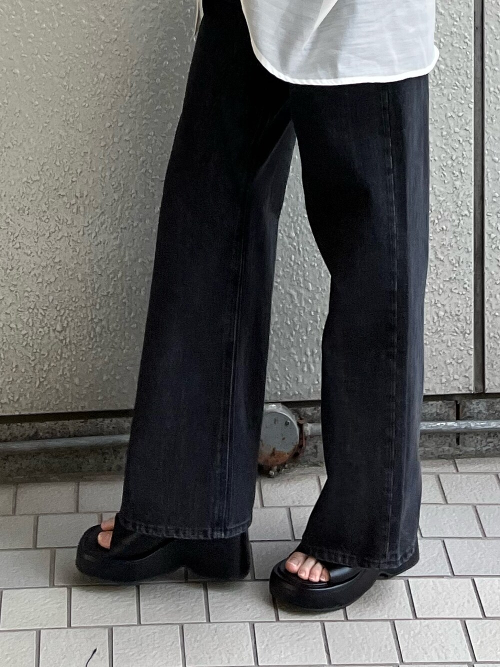 ブラック系のデニムパンツ、ブラック系のサンダル、イエロー系のタンクトップを着用したレディースの春コーディネートの7枚目の写真