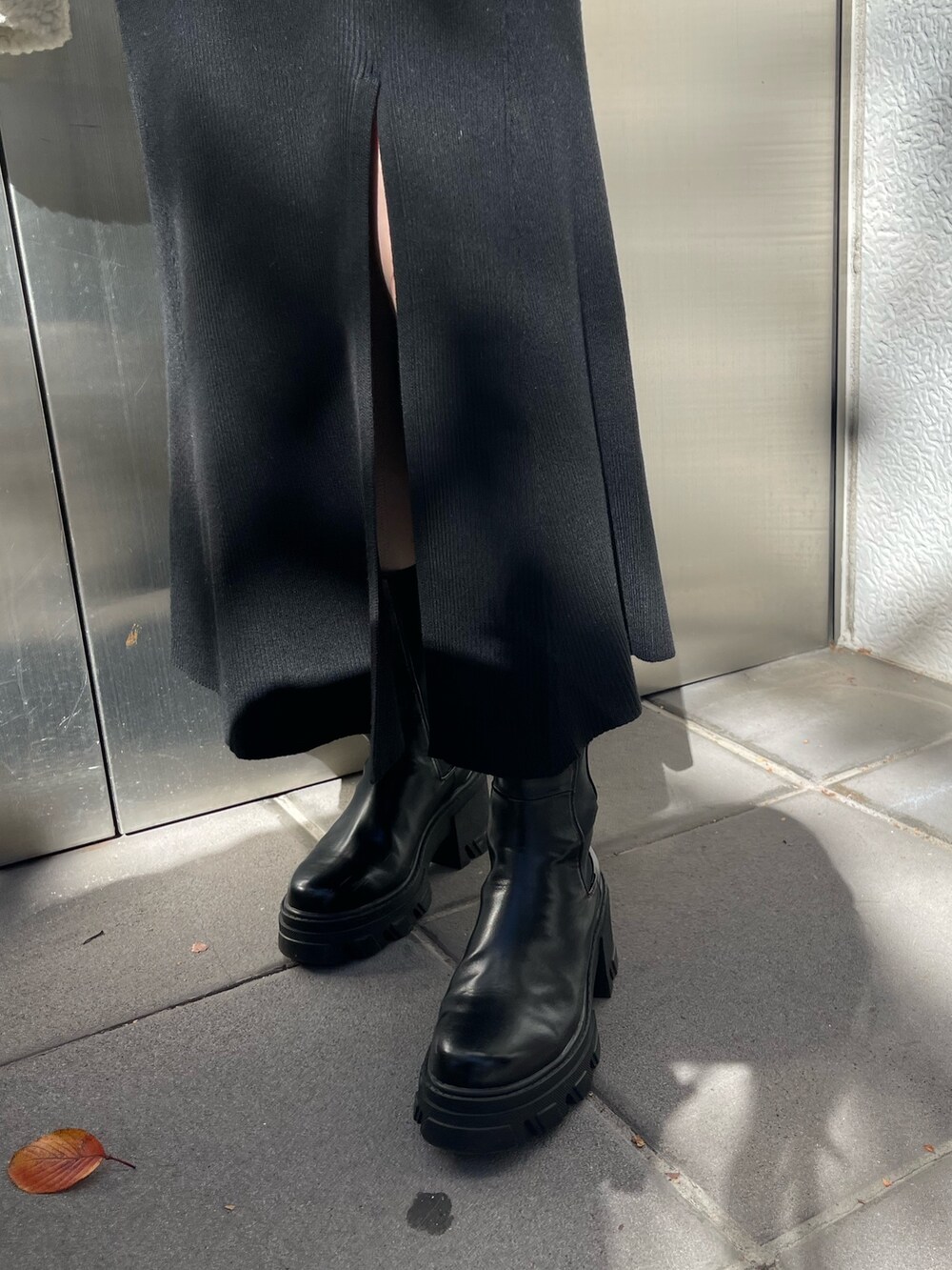 ホワイト系のダウンジャケット/コート、ブラック系のワンピース、ブラック系のブーツを着用したレディースの秋コーディネートの7枚目の写真