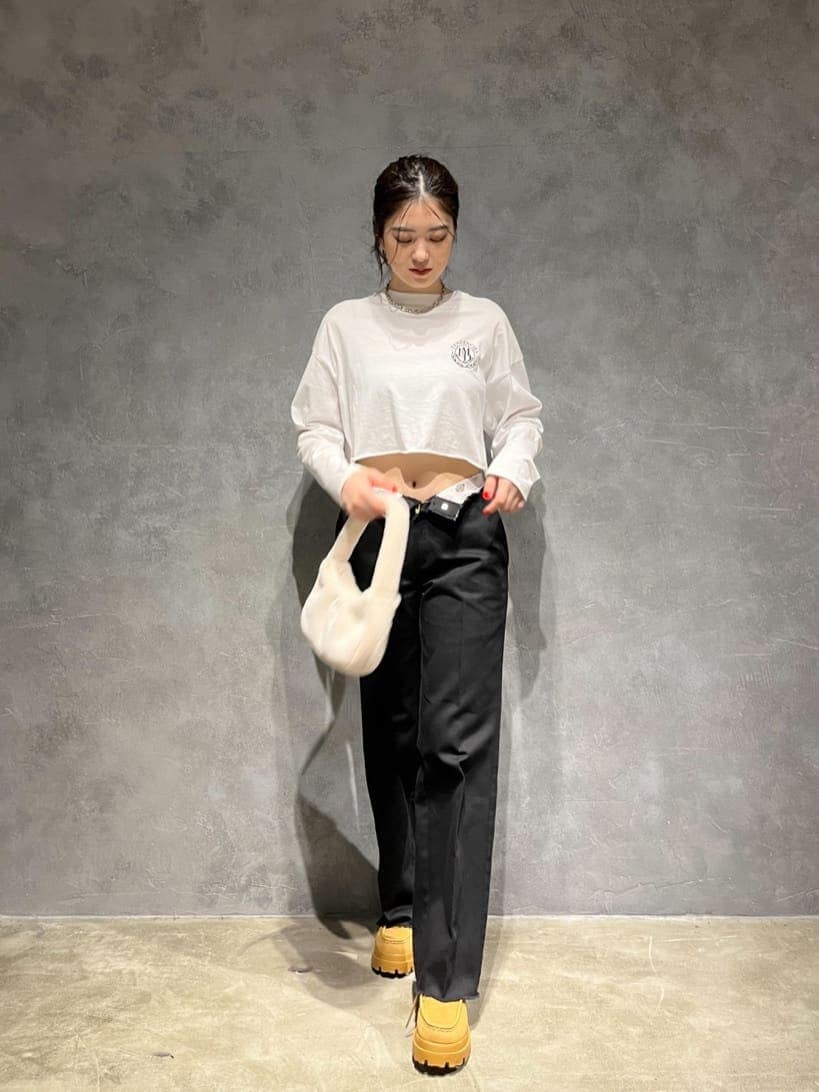 ホワイト系のハンドバッグ、ホワイト系のTシャツ/カットソー、ブラウン系のブーツを着用したレディースの秋コーディネートの2枚目の写真