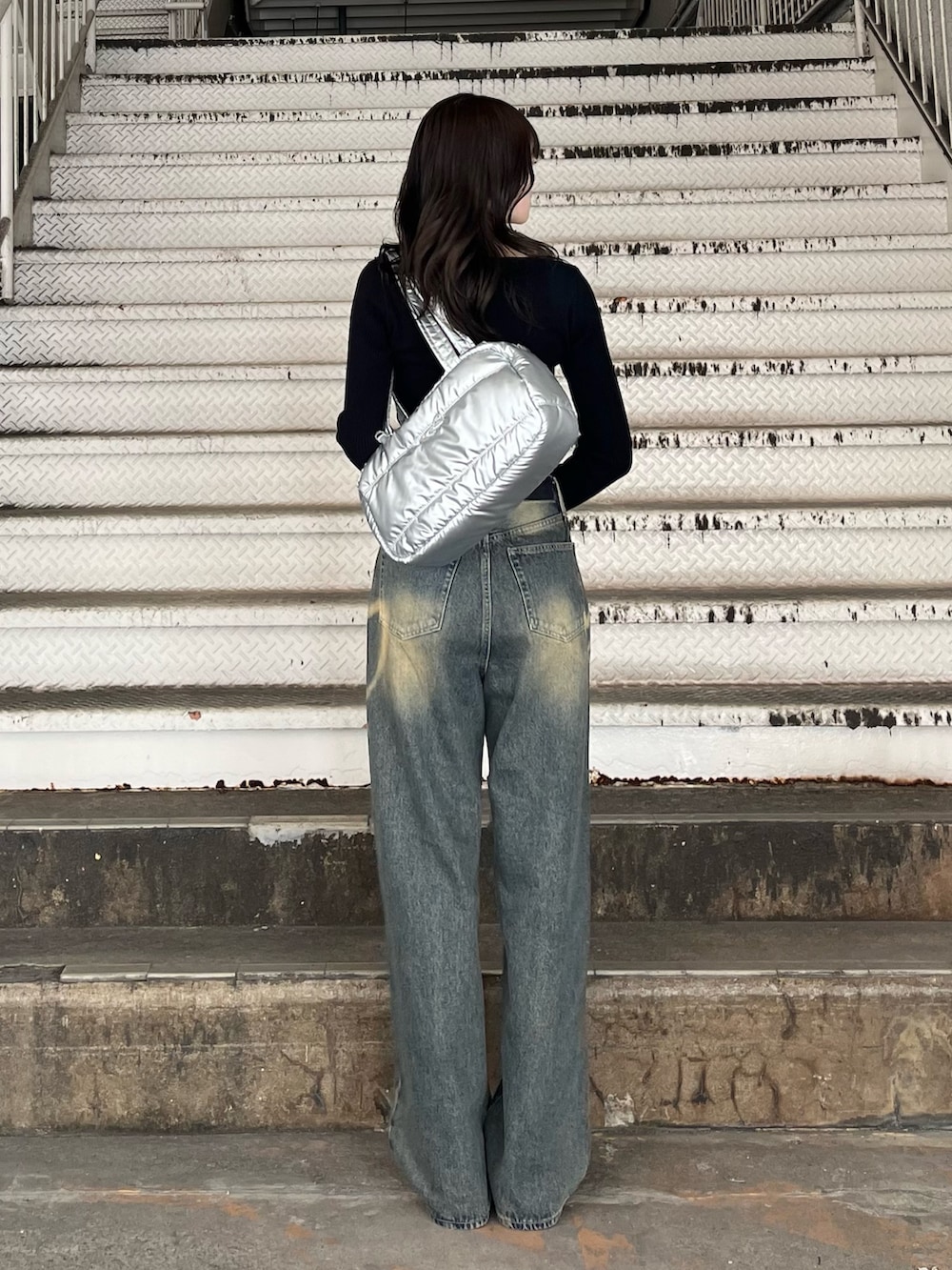 シルバー系のボストンバッグ、ブルー系のデニムパンツ、ブラック系のニット/セーターを着用したレディースの冬コーディネートの4枚目の写真