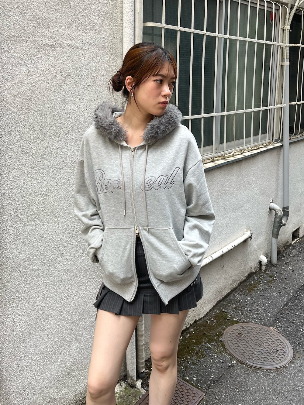 グレー系のパーカー、グレー系のスカート、ブラック系のブーツを着用したレディースの秋コーディネートの4枚目の写真