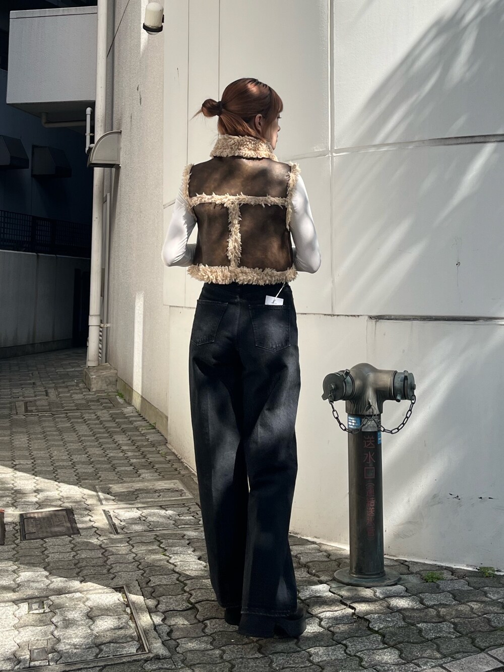 ブラック系のデニムパンツ、ブラック系のブーツ、ブラウン系のベストを着用したレディースの秋コーディネートの4枚目の写真