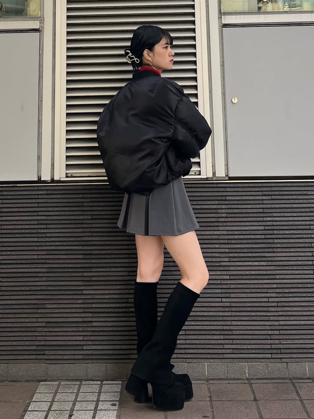 グレー系のスカート、レッド系のニット/セーター、ブラック系のブーツを着用したレディースの秋コーディネートの5枚目の写真