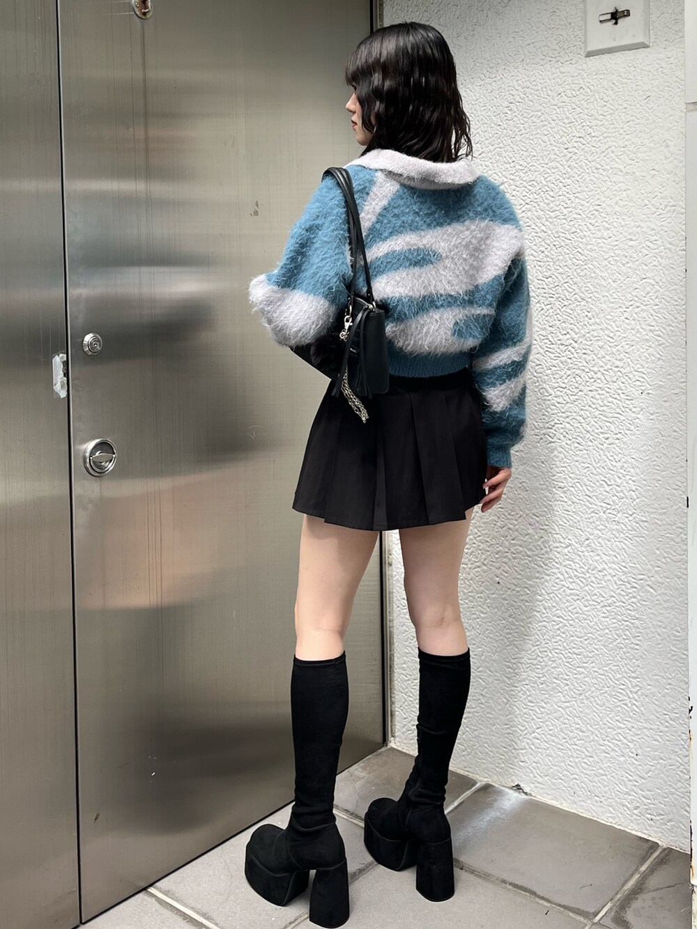 ブラック系のショルダーバッグ、ブラック系のスカート、その他のブーツを着用したレディースの秋コーディネートの3枚目の写真