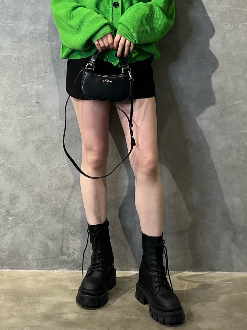 グリーン系のカーディガン/ボレロ、ブラック系のブーツ、ブラック系のスカートを着用したレディースの冬コーディネートの7枚目の写真