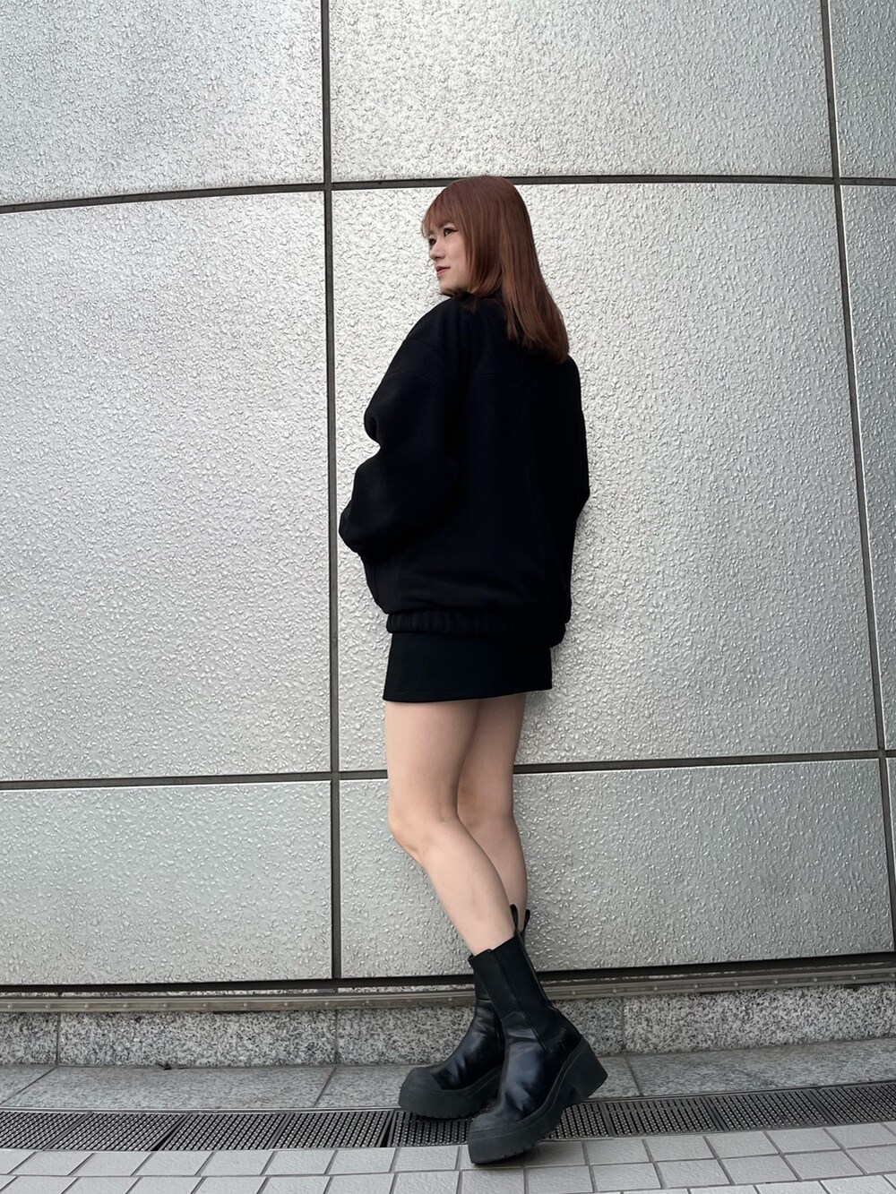 ブラック系のスカート、ブラック系のブーツ、ブラック系のブルゾンを着用したレディースの秋コーディネートの2枚目の写真