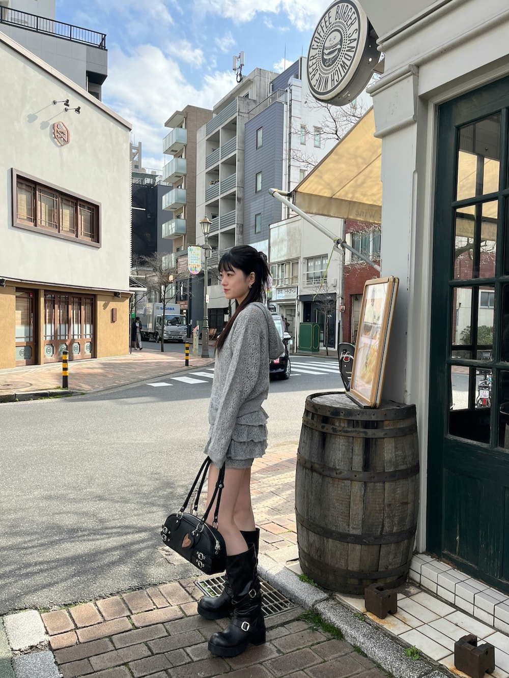 ブラック系のブーツ、ブラック系のハンドバッグ、グレー系のスカートを着用したレディースの春コーディネートの2枚目の写真