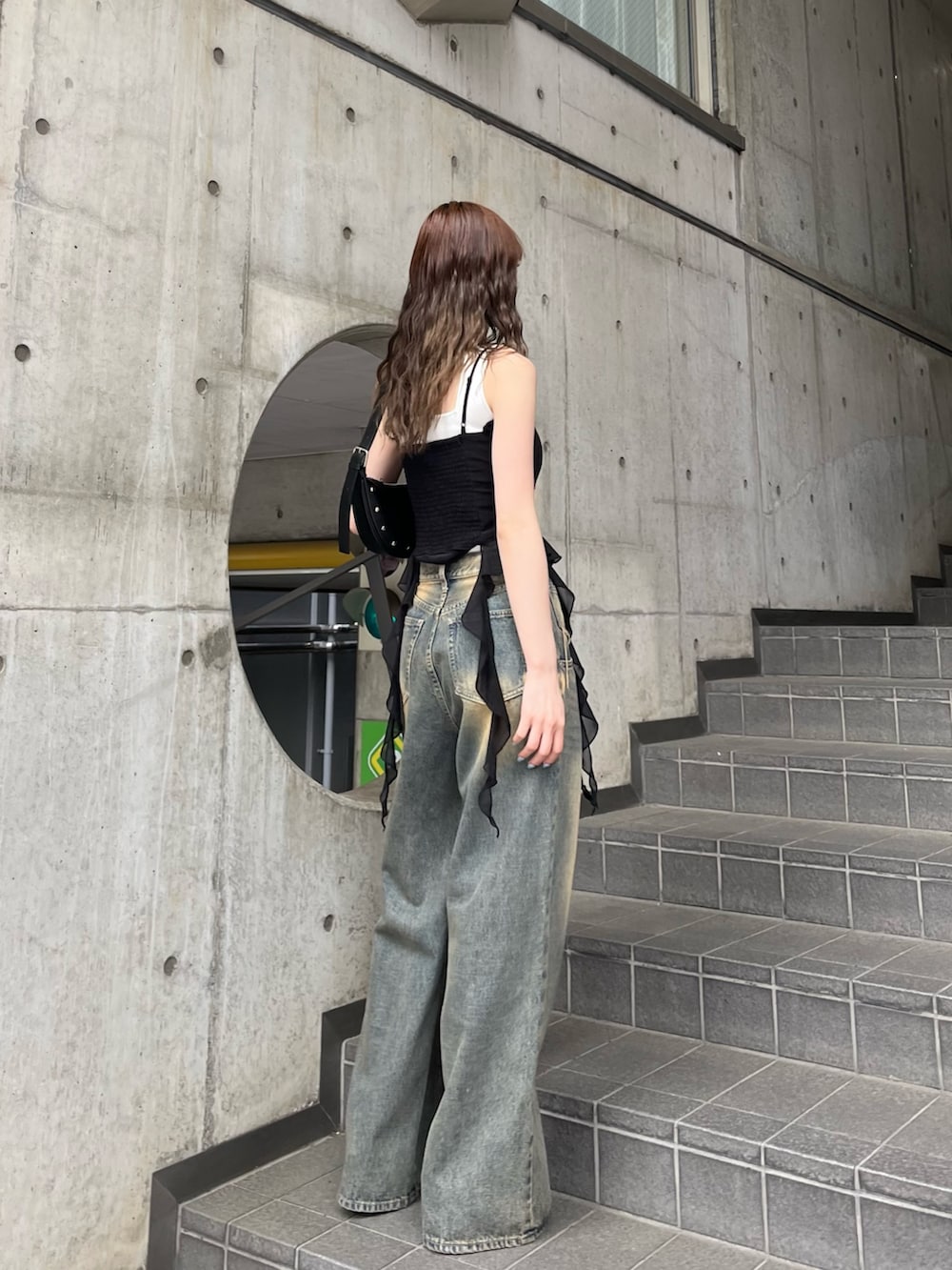 ブラック系のパンプス、ブラック系のTシャツ/カットソー、ブルー系のデニムパンツを着用したレディースの春コーディネートの3枚目の写真