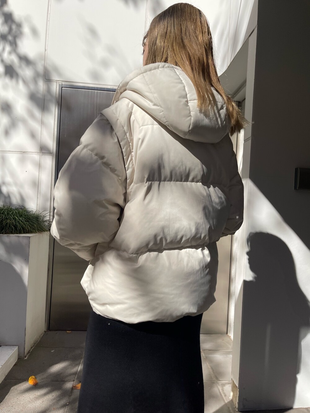 ホワイト系のダウンジャケット/コート、ブラック系のワンピース、ブラック系のブーツを着用したレディースの秋コーディネートの6枚目の写真