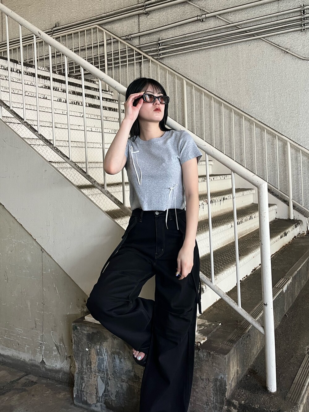 ブラック系のデニムパンツ、グレー系のTシャツ/カットソー、ブラック系のサンダルを着用したレディースの夏コーディネートの6枚目の写真