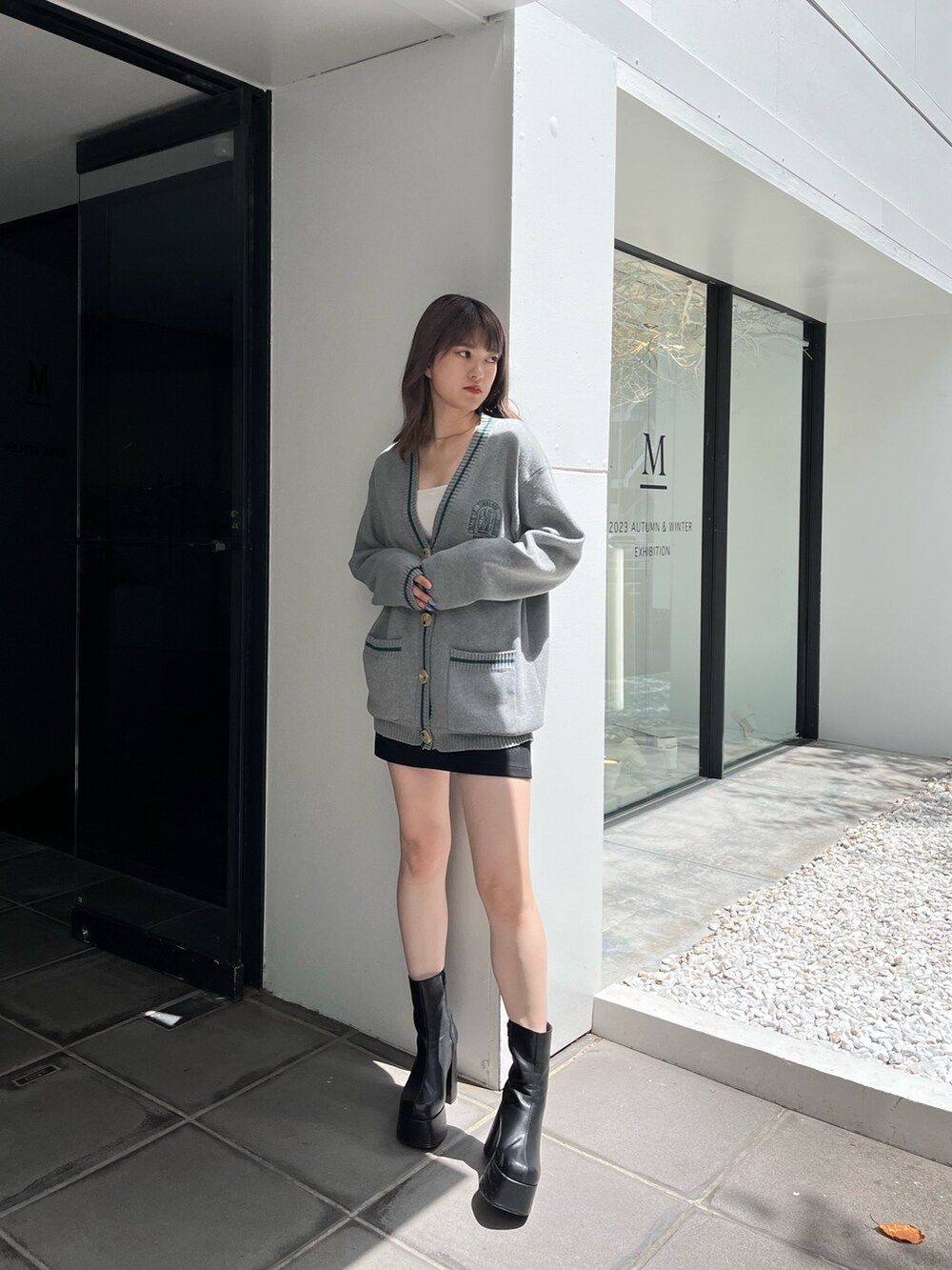 グレー系のカーディガン/ボレロ、ブラック系のスカート、ブラック系のブーツを着用したレディースの夏コーディネートの2枚目の写真