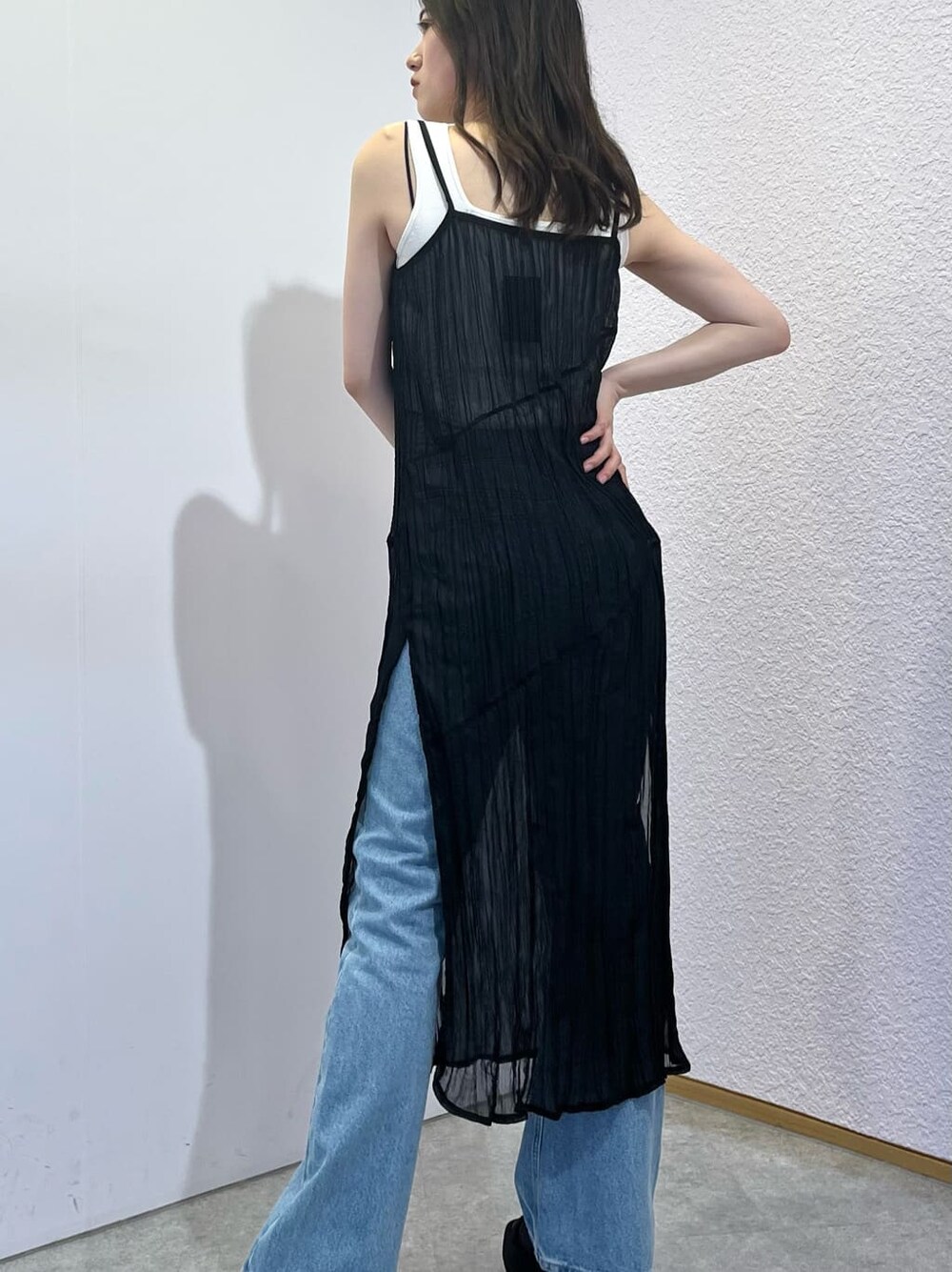 ホワイト系のタンクトップ、ブラック系のワンピース、ブルー系のデニムパンツを着用したレディースの夏コーディネートの4枚目の写真