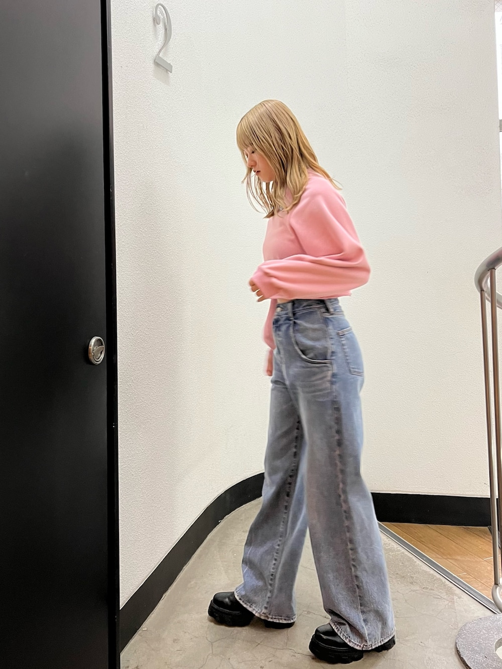 ブルー系のデニムパンツ、ブラック系のブーツ、ピンク系のスウェットを着用したレディースの冬コーディネートの3枚目の写真