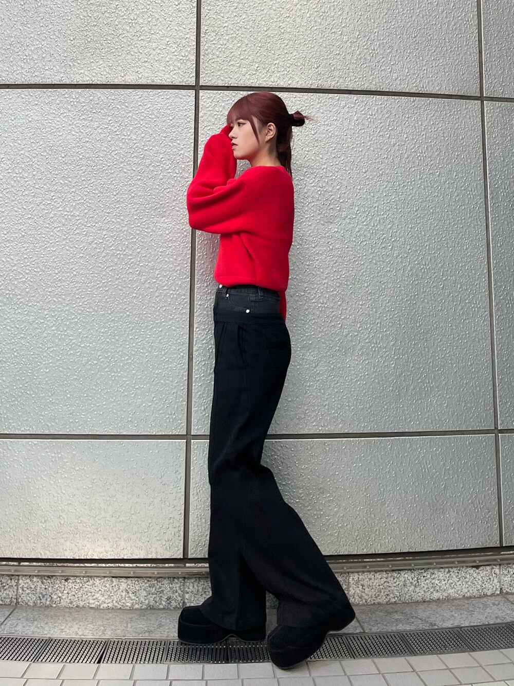 レッド系のニット/セーター、ブラック系のデニムパンツ、ブラック系のブーツを着用したレディースの冬コーディネートの3枚目の写真
